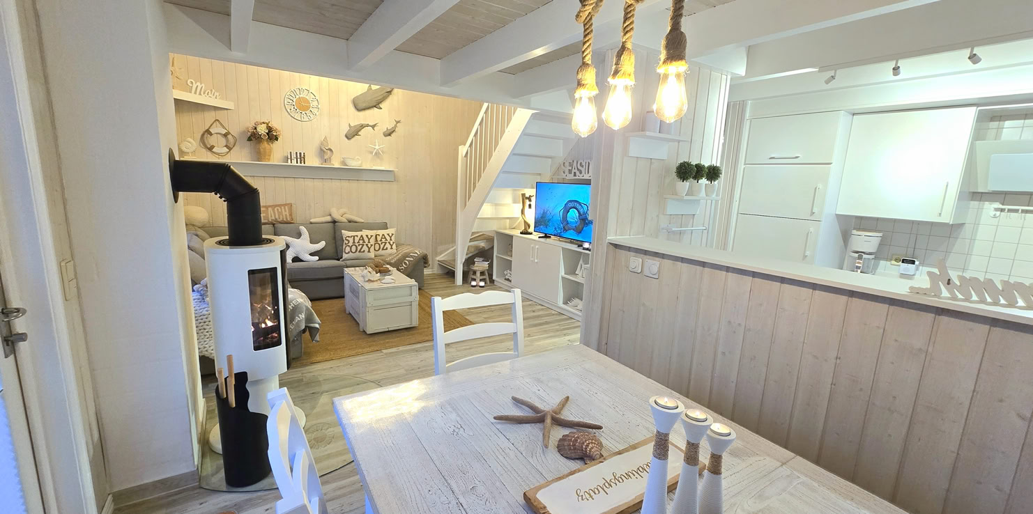 Helle Küche mit weißen Schränken, einem Herd, einer Spüle und rosa Dekorationen. Ein Fenster und eine Glastür im Hintergrund.